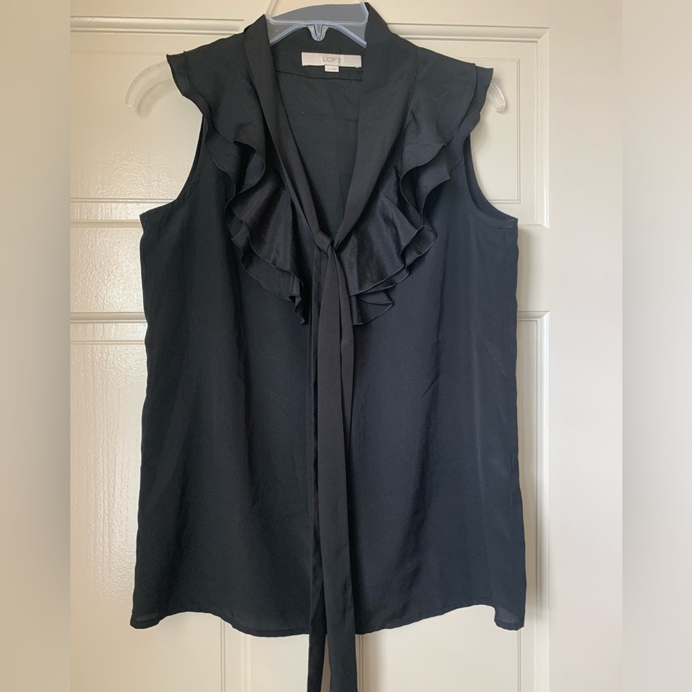 Black sleeveless top with ruffle neck and front tie.